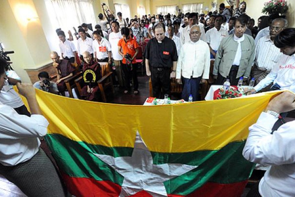 Myanmar people from different religions pay their respect in front of Myanmar's national flag during a multi-confessional peace ceremony in Yangon on Thursday. Photo: AFP