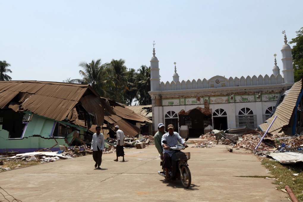 Men ride on a motorbike as others remove debris from a destroyed mosque, in Gyobingauk, about 125 miles from Yangon, Myanmar. Photo: AP