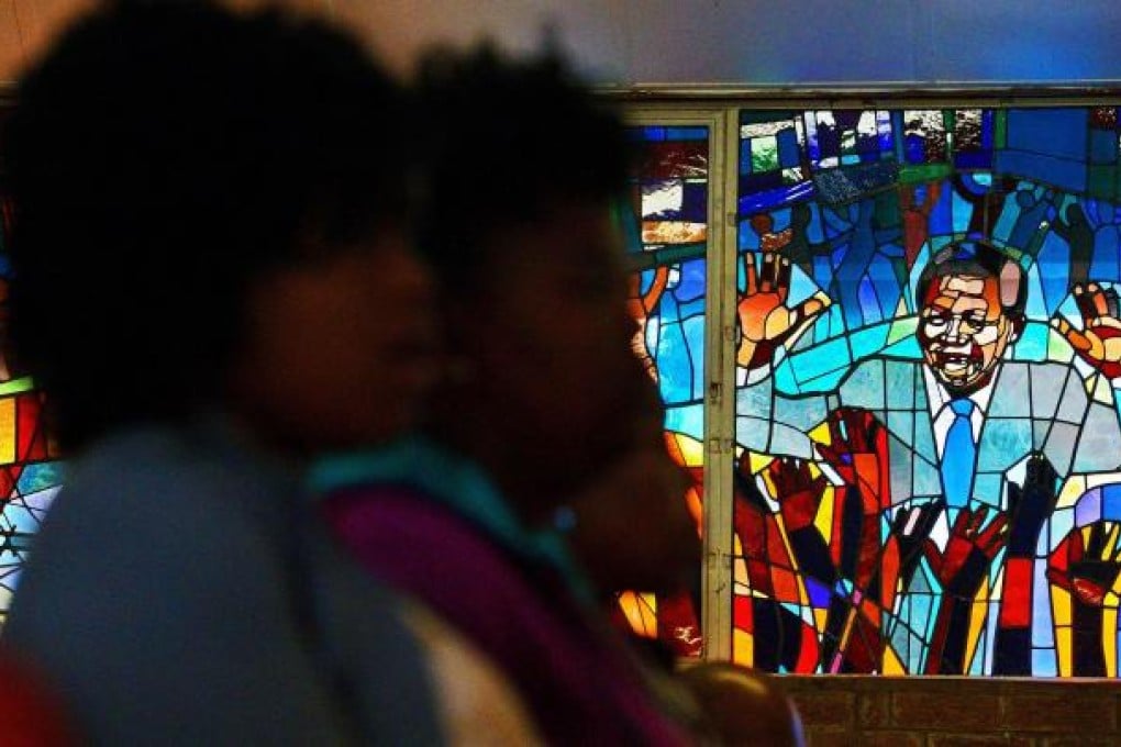 Catholics pray in Regina Mundi church in Soweto, in front of a stained glass window depicting Nelson Mandela. Photo: AFP