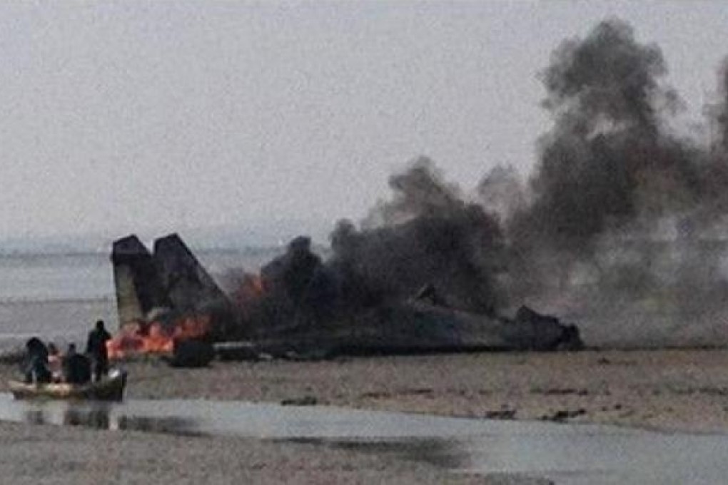 The wreckage of the fighter plane is englufed by flames after it crashed on mudflats. Photo: SCMP Pictures