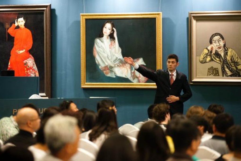 A worker shows off the various artwork up for bidding at the Poly 2012 Spring Art Auction in Beijing. Photo: AFP