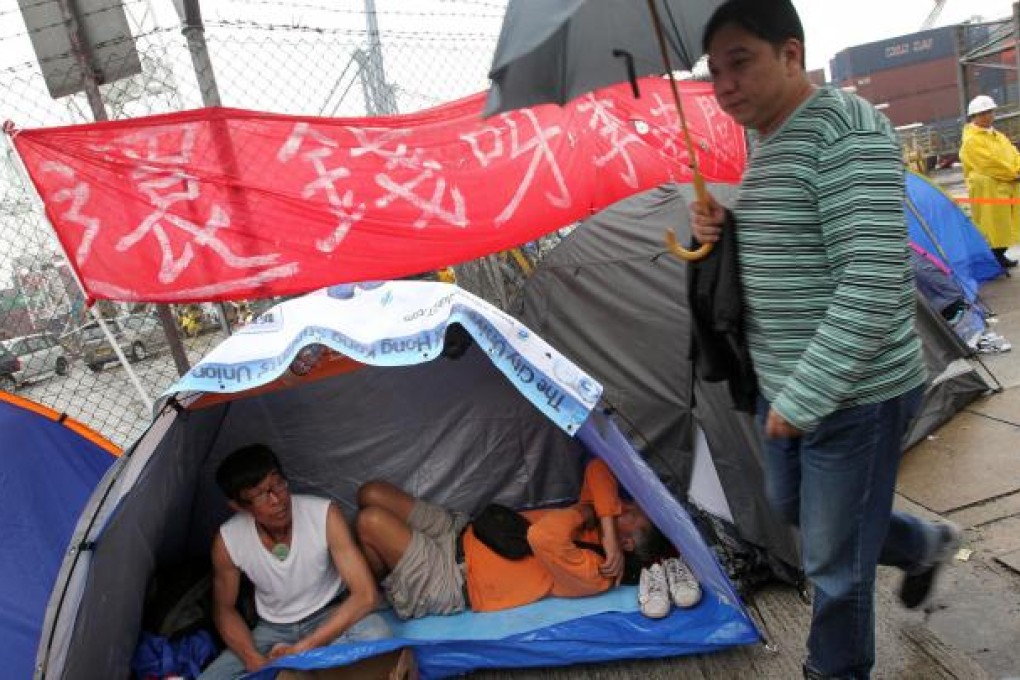 Two striking dock workers set up camp in Kwai Tsing, under a banner demanding that tycoon Li Ka-shing, whose Hutchison Whampoa conglomerate controls the nearby container terminals, should give them back their money. The strikers want a 17 per cent pay rise and say they have not received any increase for a decade. Photo: K.Y. Cheng