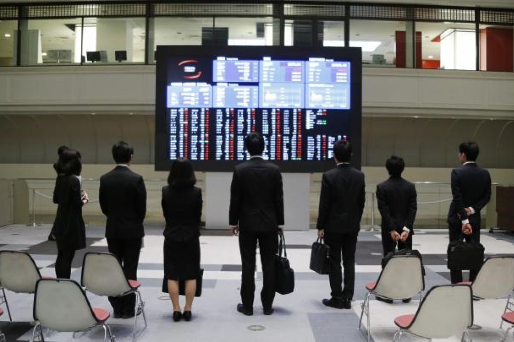 Spectators look at stock prices at the Tokyo Stock Exchange on Friday. The market gained 1.6 per cent at the close after earlier jumping about five per cent. Photo: AP
