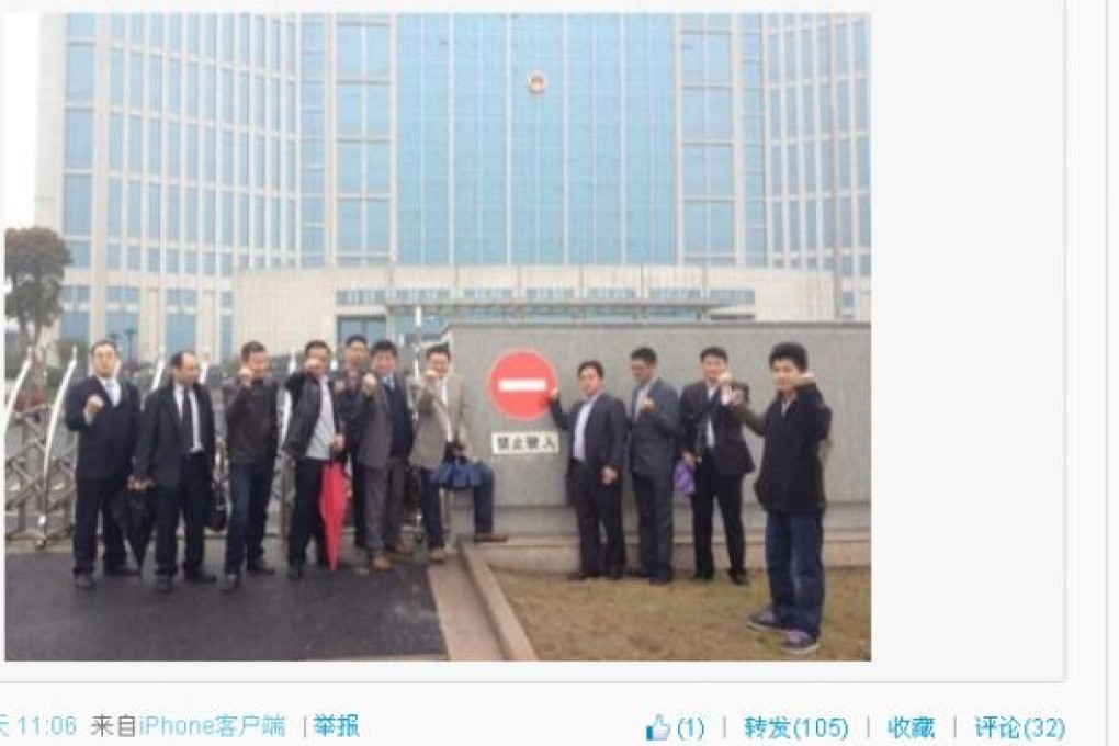 A photo shared on Weibo shows twelve men raising their fists at the Jingjiang courthouse on Friday. (Photo: Weibo)