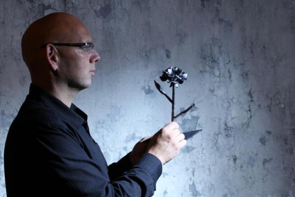 Yaron Bob with one of the roses he makes with metal taken from rockets and spent artillery fired into Israel. Photo: Nora Tam