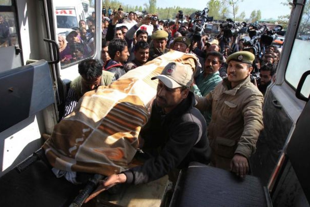 Crowds watch as police place the body of the woman tourist in an ambulance in Srinagar. Photo: EPA