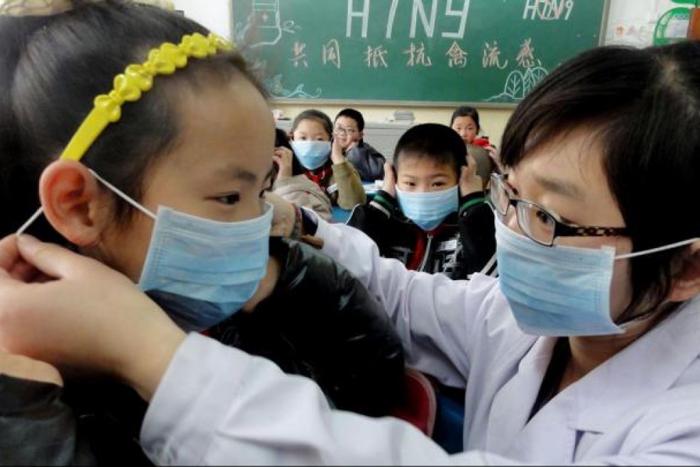 A teacher at an elementary school in Jinan, capital of Shandong province, instructs a pupil yesterday on the proper way to wear a mask. The elementary school was offering a class on how to prevent bird flu as health authorities on the mainland took more steps to cope with an increasing number of H7N9 bird flu cases. Photo: Xinhua