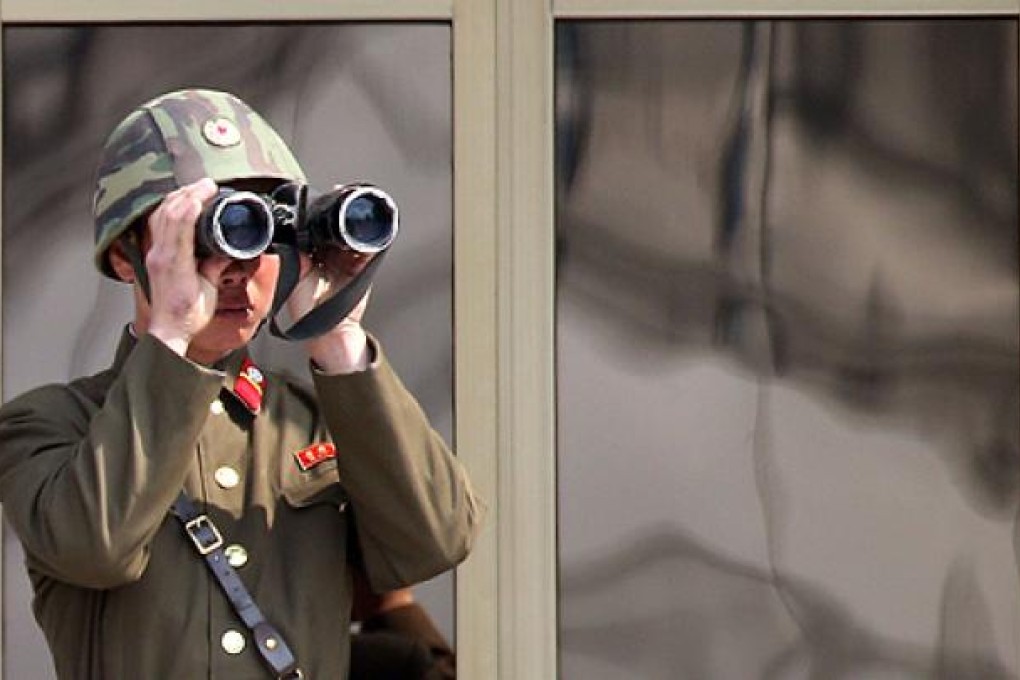 A North Korean soldier looks through binoculars at a village in the demilitarised zone. Photo: AFP