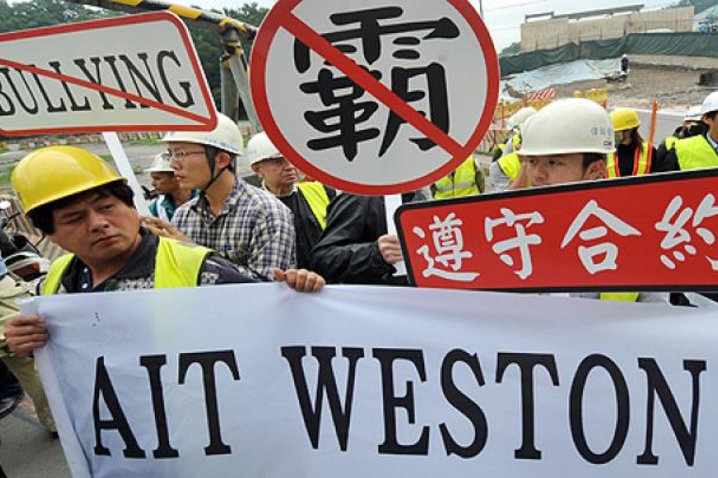 Taiwanese workers chant slogans while holding protest signs at the construction site of a new office complex of American Institute in Taiwan during a demonstration in Taipei on Monday. Photo: AFP
