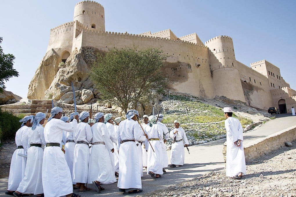 Men in costume perform a traditional Razha dance outside Nakhal Fort.