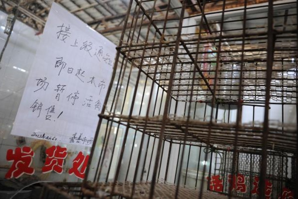 A notice alongside empty cages says the poultry stalls at a Shanghai market are closed. Photo: AFP