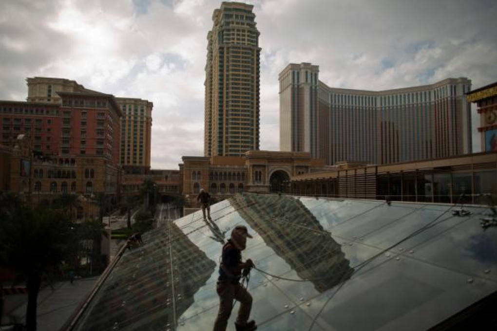 Workers clean the glass roof of a shopping mall in front of the Las Vegas Sands-owned Four Seasons Hotel Macao. Photo: Bloomberg