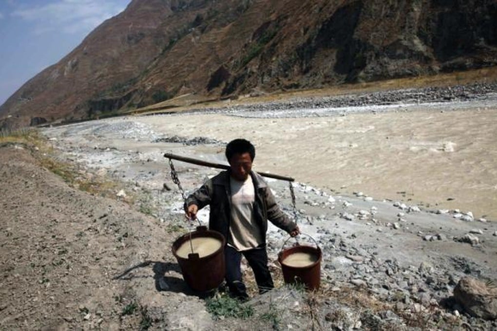 A villager carries buckets of water to be used for drinking from a white polluted stream in Dongchuan district of Kunming, Yunnan province. Photo: Reuters