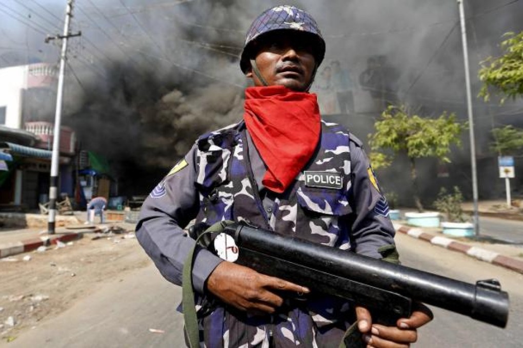 An officer on guard during the deadly riots in Meiktila. Photo: EPA