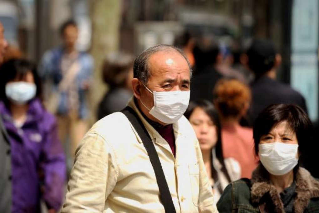 People wear masks to protect themselves from bird flu on a street. Photo: AFP