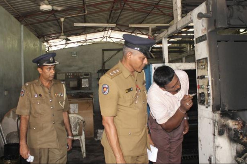 Police officers inspect the burnt printing machines in the Uthayan. Photo: Reuters