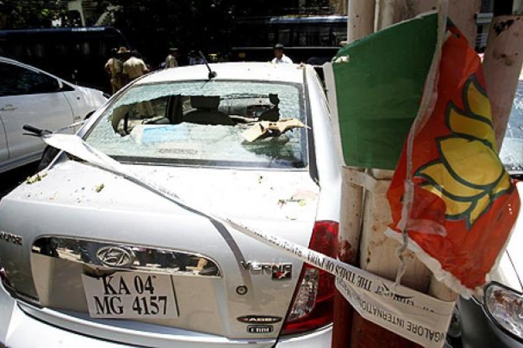 A partly torn poster of India's main opposition Bharatiya Janata Party (BJP) hangs on an electric pole next to a car, damaged in an explosion in a residential neighbourhood near the BJP office, in Bangalore, India, on Wednesday. Photo: AP