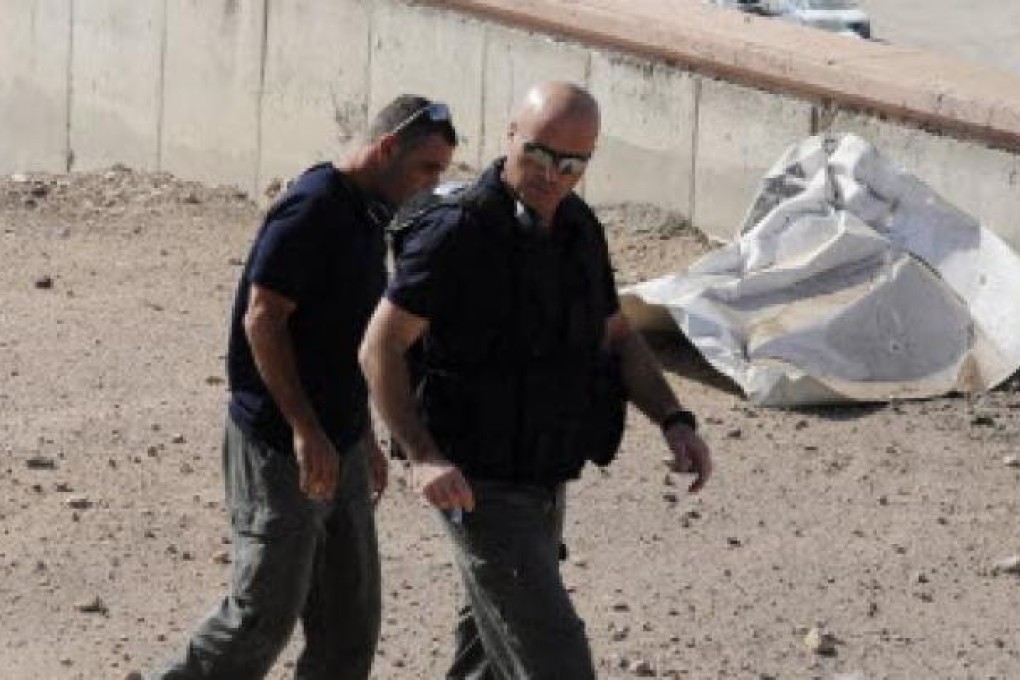 Israeli police explosives experts walk near a rocket which was fired into the Red Sea resort city of Eilat. Photo: Reuters