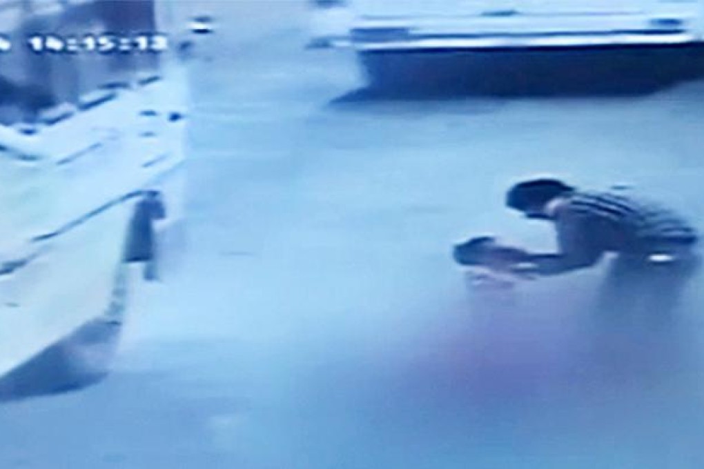 An accident victim in Jaipur, standing next to the bodies of his wife and daughter, consoles his son as vehicles pass by the scene of the accident without providing help. Photo: AFP