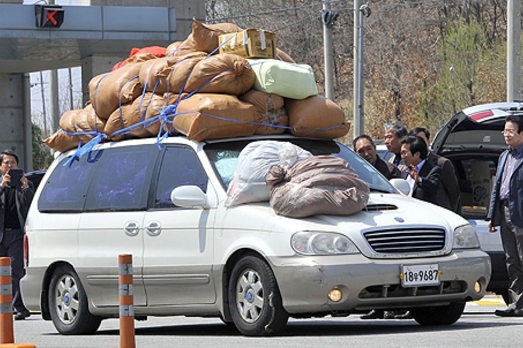 South Korean representatives of the business companies at Kaesong greet a car carrying sacks of clothes made in North Korea's Kaesong joint industrial complex on Wednesday. Photo: AFP