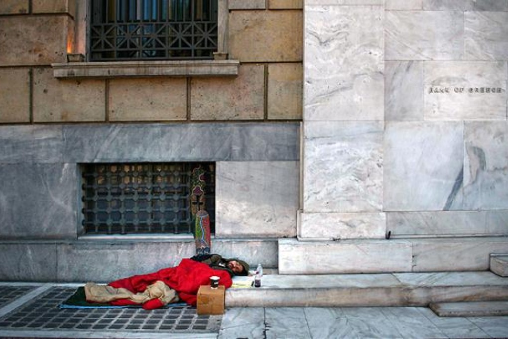 A homeless man sleeps outside the headquarters of the Bank of Greece in Athens