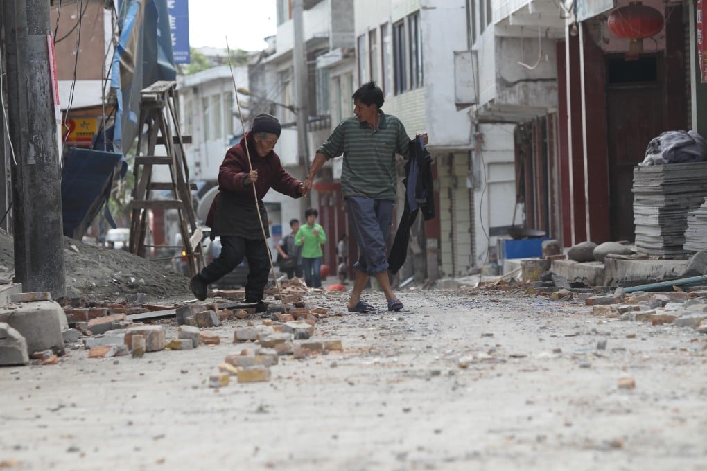 A man helps an old woman walk in the rubble in Luyang, Sichuan after the 7.0 magnitude earthquake on April 20. Photo: Simon Song