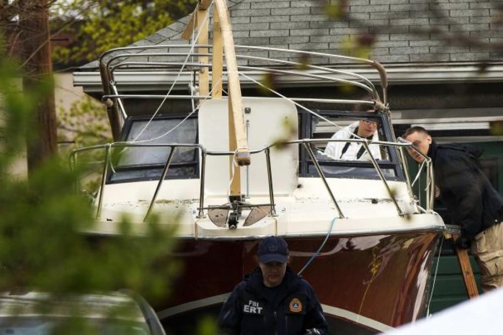 FBI investigators study the boat in Dave Henneberry's garden in Franklin Street, Watertown, where the suspect was found. Photo: Reuters