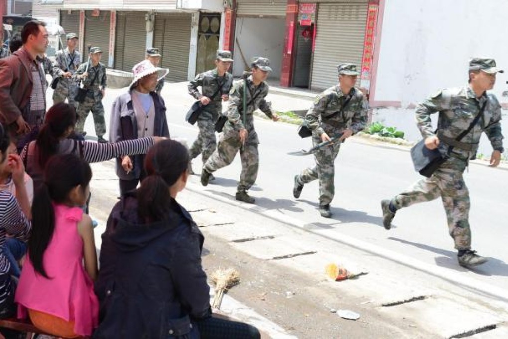 Soldiers run past residents of Longmen to assist in relief operations. Photo: Xinhua