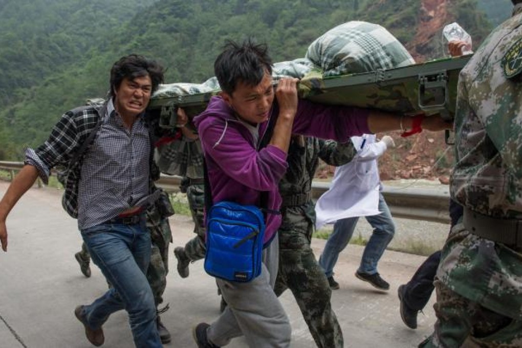 Volunteers Yang Chengcheng and Xiao Long help rush an injured woman to medical facilities in Longmen township. The two students ran 10km over damaged roads. Photo: Xinhua