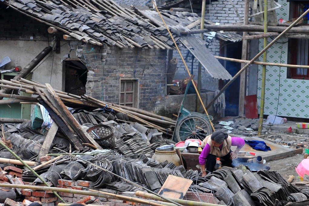 A woman sifts through the debris of her destroyed house in Longmen Township,  Lushan County. Photo: Xinhua