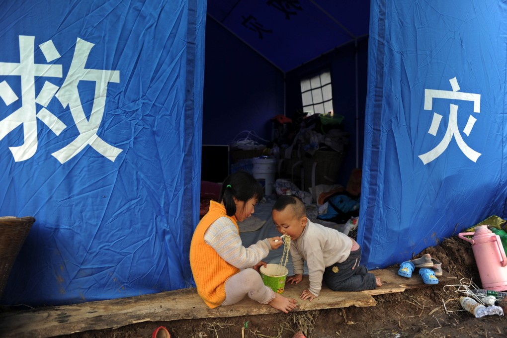 Children have instant noodles outside their tent in Lushan county. Photo: Reuters