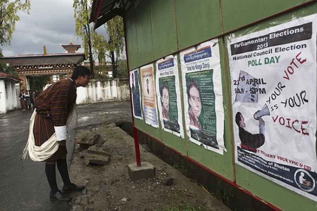 A Bhutanese man in traditional attire looks at posters of candidates on the eve of polling to the upper house National Council in Samdrup Jonkhar. Photo: AP