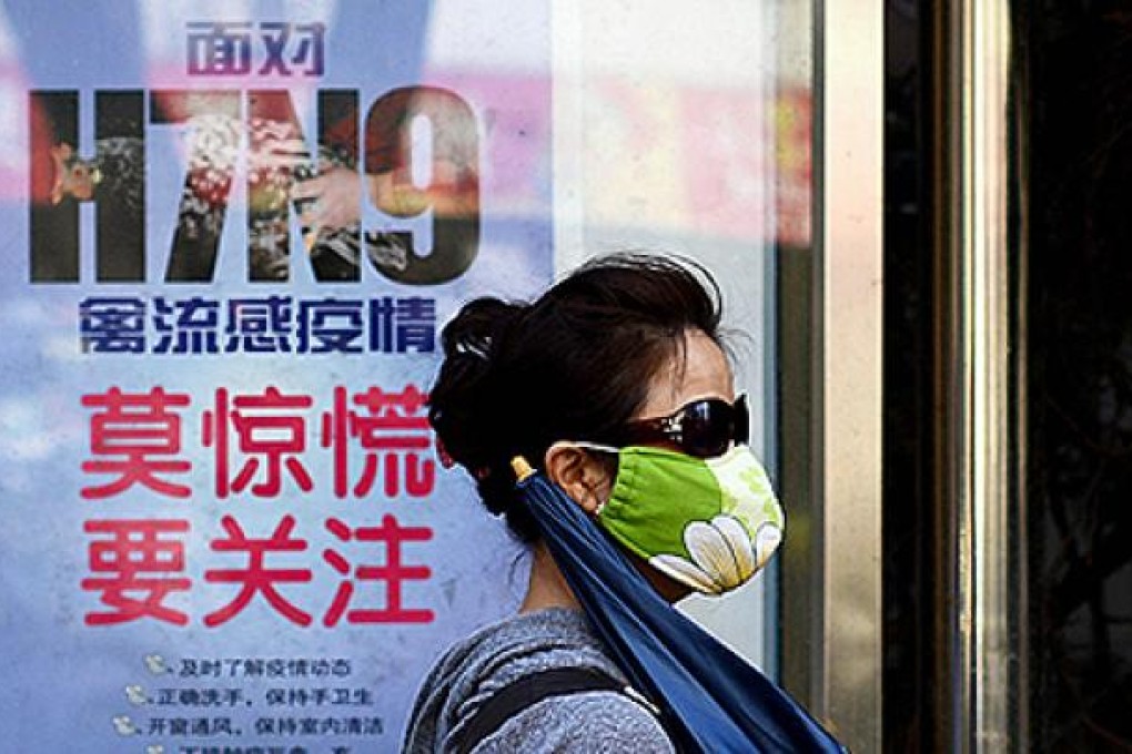 A woman wears a face mask as she walks past a poster showing how to avoid the H7N9 avian influenza virus. Photo: AFP