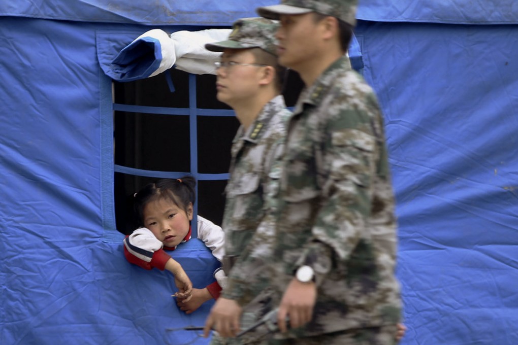 A girl looks out from a tent set up at a temporary settlement in Longmen township. Photo: EPA