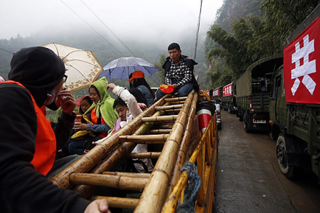 Volunteers wait in the rain after a road was blocked due to a fallen boulder in Taiping, Lushan county. Photo: EPA