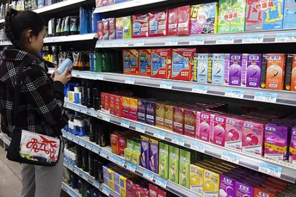 A woman browses items for sale beside a shelf of condoms at a supermarket in Beijing. Photo: AFP