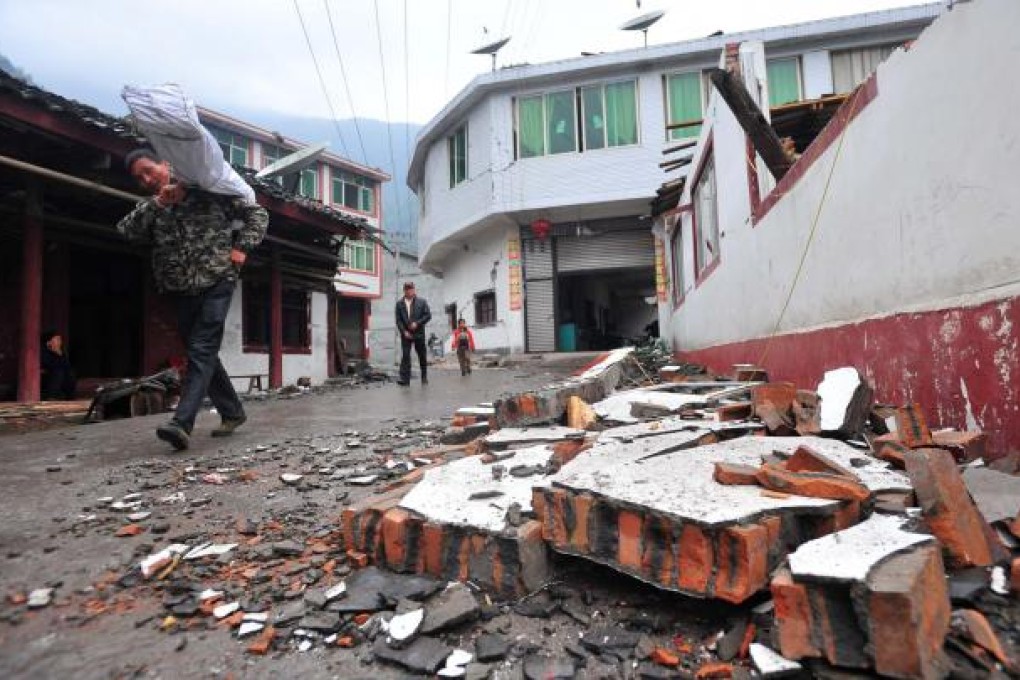 Villagers walk past a damaged house in quake-hit Yuxi village of Lushan county, Sichuan province. Photo: Xinhua