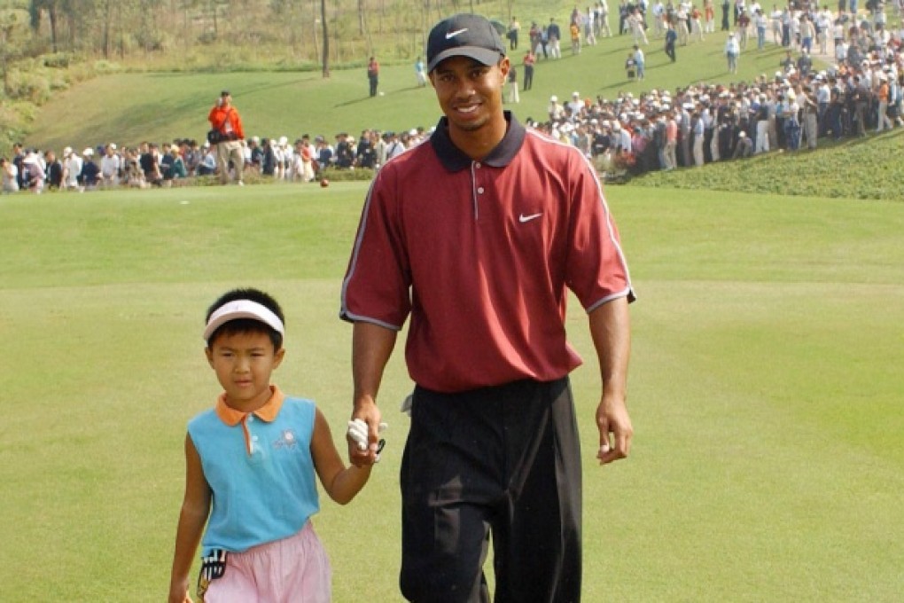 Tiger Woods walks with young Cindy Fongyue at Shenzhen's Mission Hills Golf Club in 2001.