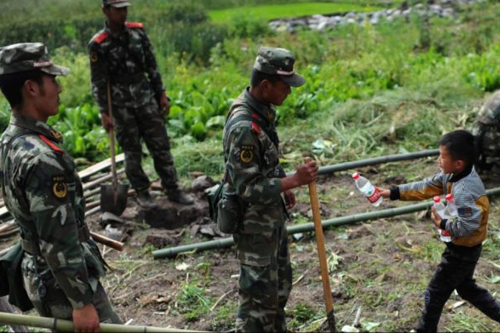 A child hands out water to People's Armed Police helping survivors of Saturdays' earthquake in Yaan, Sichuan province. Photo: AFP