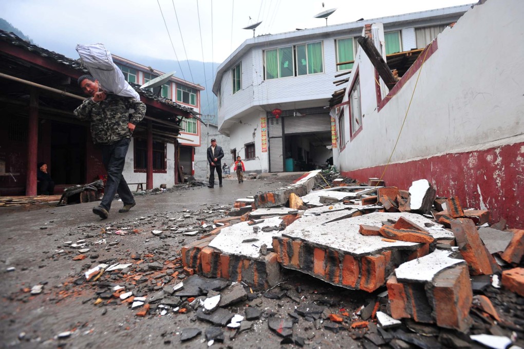 Villagers walk past a damaged house in quake-hit Yuxi Village of Lushan County. Photo: Xinhua