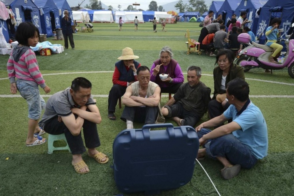 People displaced by the April 20 earthquake in Sichuan watch television near their tents in Lushan county's Longmen township. Photo: Reuters