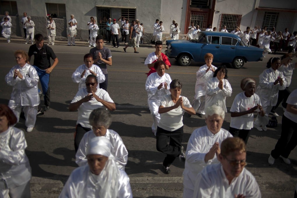 People attend a mass Tai Chi session in the street as a classic American car drives past in the Chinatown area of Old Havana, Cuba. Photo: AP