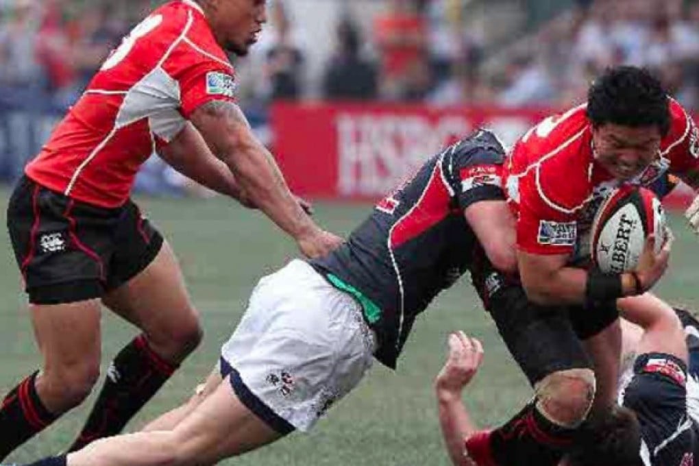 Hong Kong hooker Alex Harris (centre) tackles Japan’s Harumichi Tatekawa in their Asian Five Nations match yesterday. Photo: Jonathan Wong
