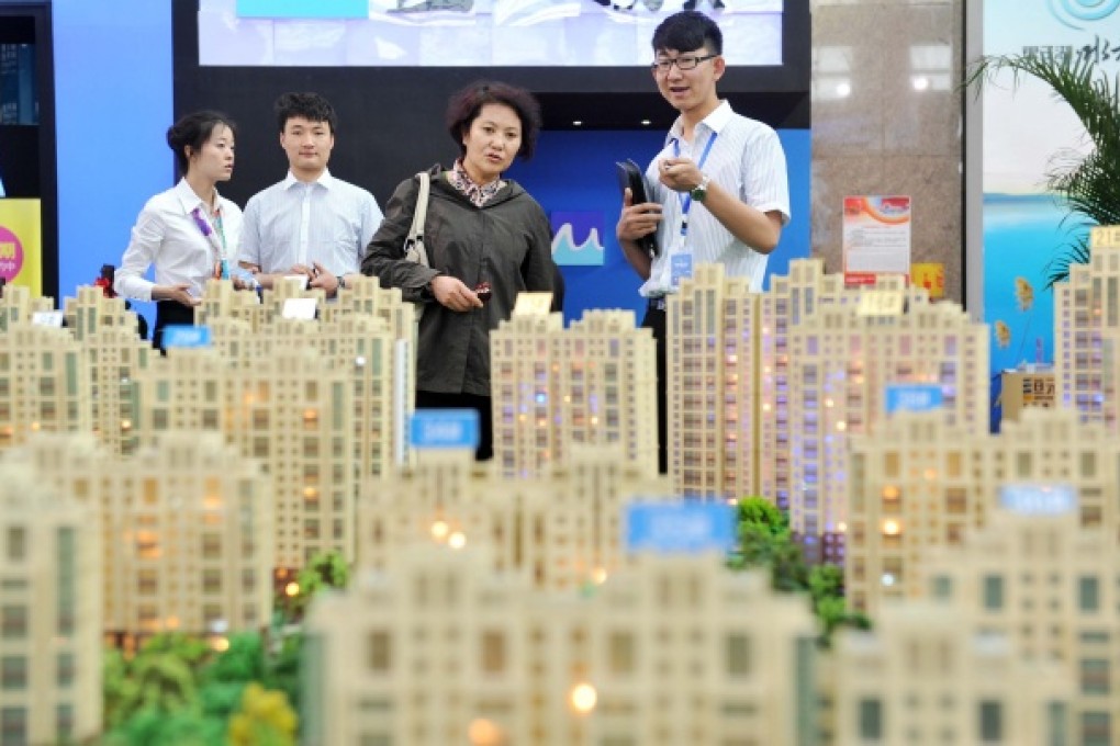 A visitor learns housing information in front of the model of a residential housing project during the 5th Western China House and Automobile Fair in Yinchuan. Photo: Xinhua