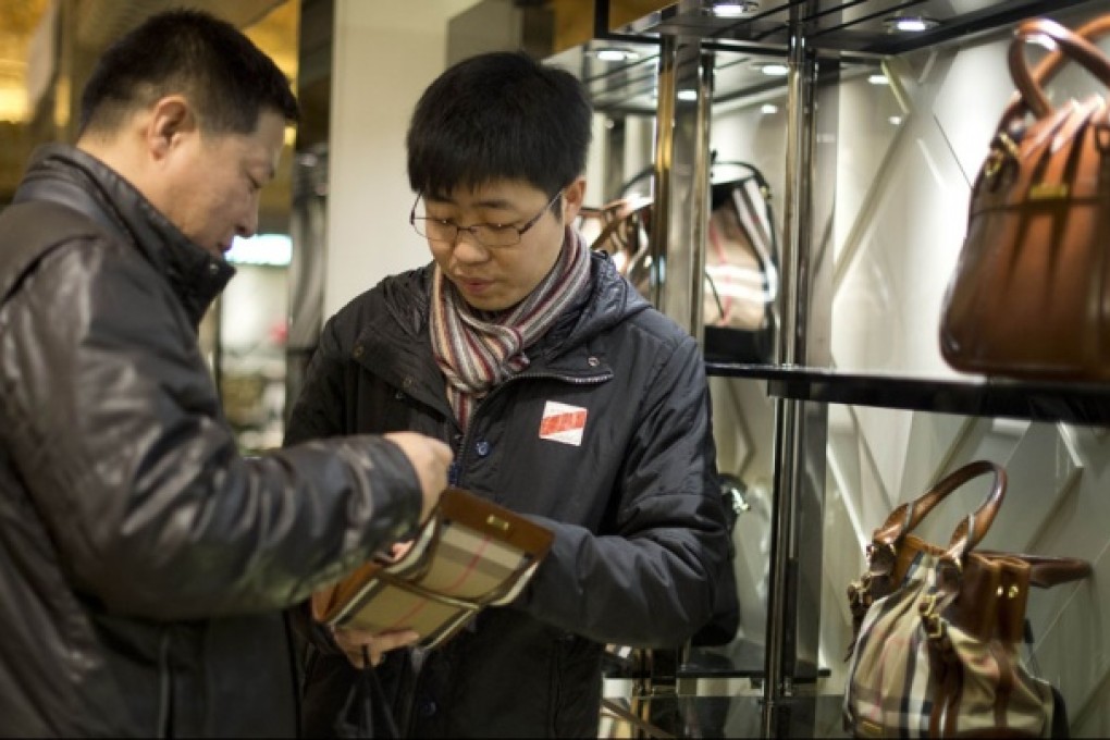 A Chinese couple visiting the exclusive Harrods department store in London consider splashing out on an expensive handbag. Photo: AFP