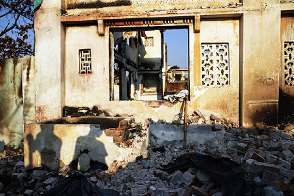 People cast shadows as they collect bricks and useful items from burnt Muslim homes in Meikhtila. Photo Reuters