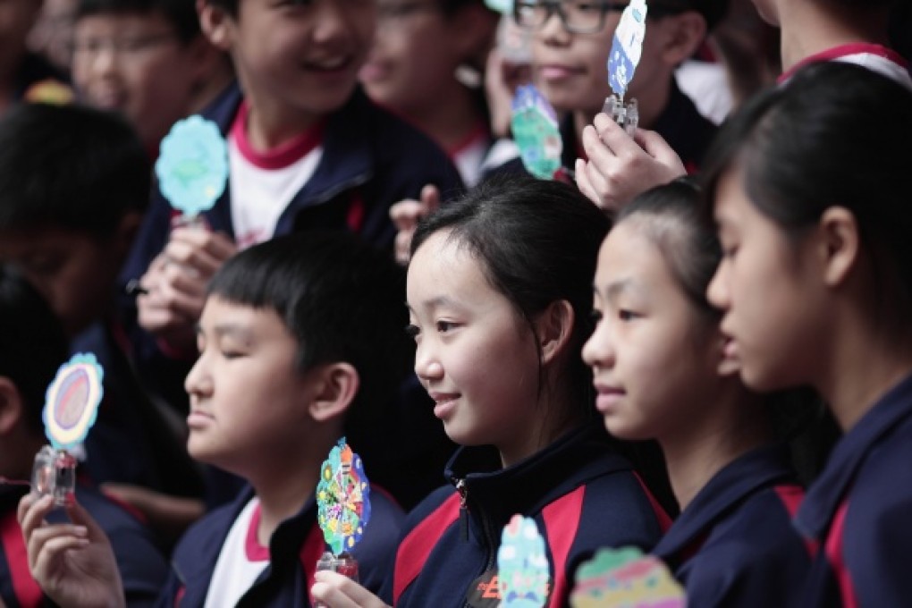 Local school children hold 'dancing solar flowers' during the installation of an art piece by French artist Alexandre Dang in Hong Kong. Photo: AFP