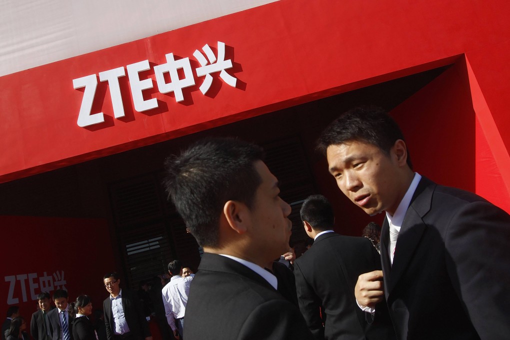 Guests and employees chat under a ZTE company logo in front of the venue of the company's 15th anniversary celebration in Beijing. Photo: Reuters
