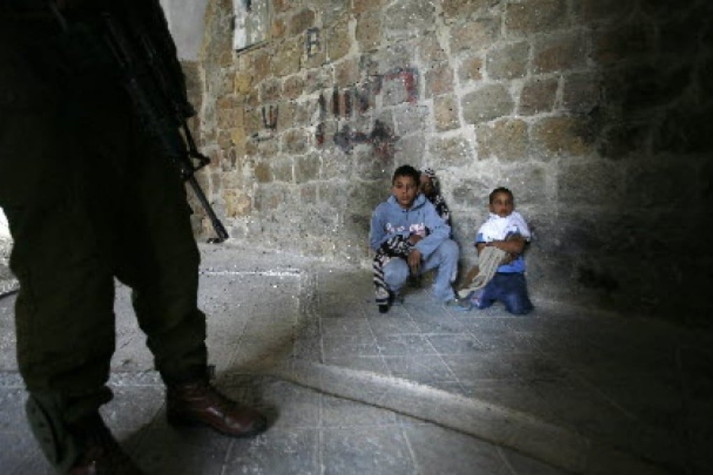 An Israeli soldier stands next to three Palestinian boys in the West Bank. While Israel may not face a third Palestinian intifada, the security situation in the West Bank still remains fragile.