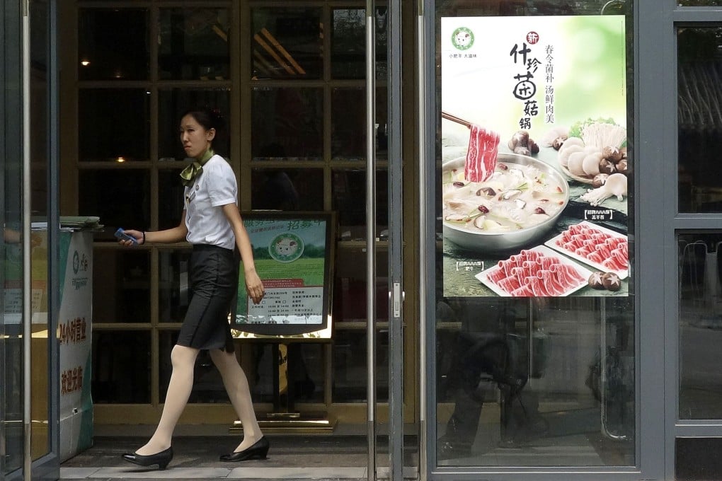 A hostess waits for customers at the entrance of a Little Sheep hotpot restaurant in Beijing. Photo: AFP